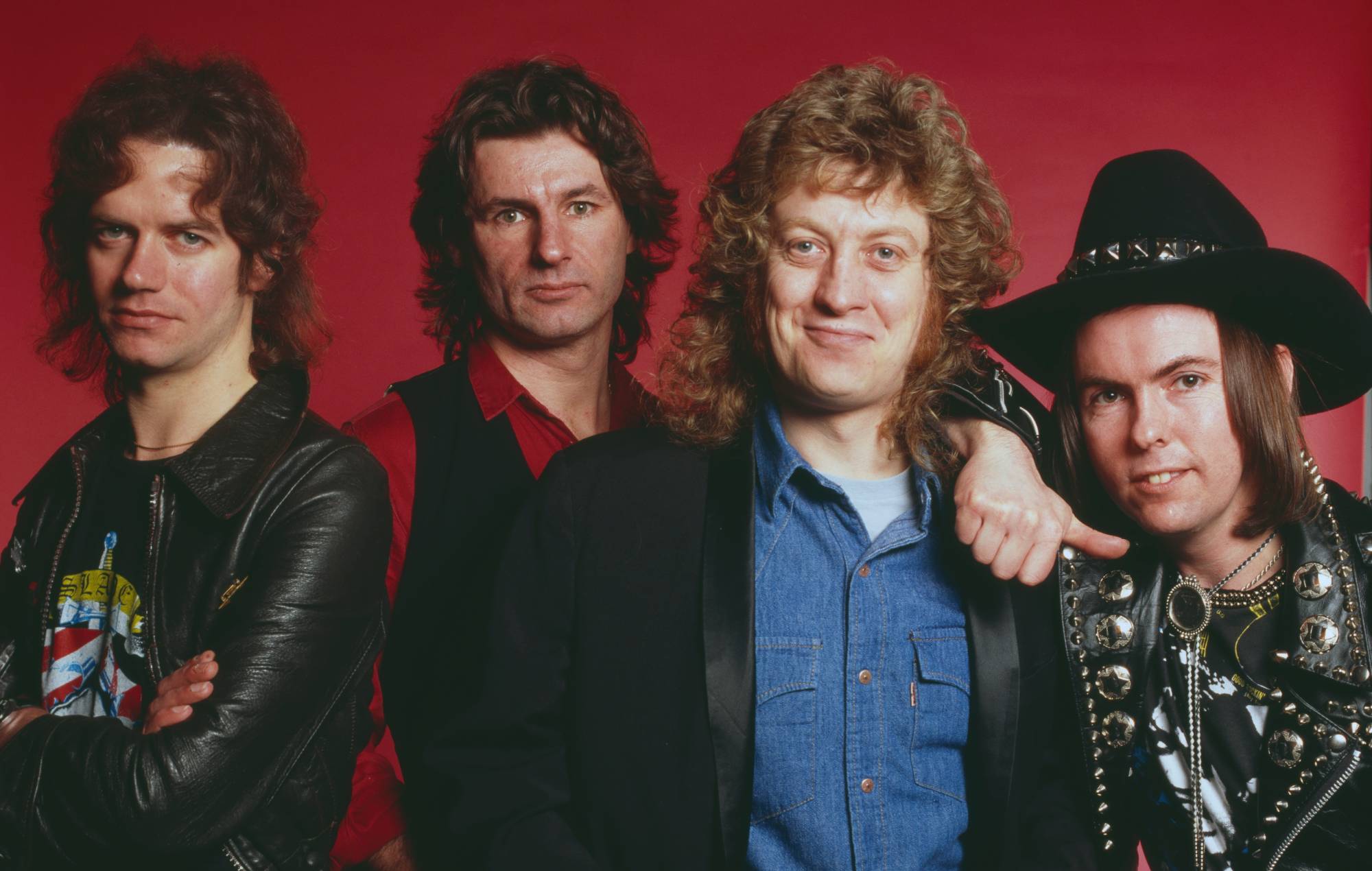 Studio portrait of English rock group Slade, posed in London circa 1975. The band are, from left: bassist Jim Lea, drummer Don Powell, singer Noddy Holder and guitarist Dave Hill wearing leather jacket with metal studs. (Photo by Michael Putland/Getty Images